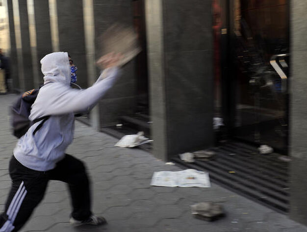 Un joven lanza piedras y bolas de pintura contra un banco.

Foto: AFP Photo
