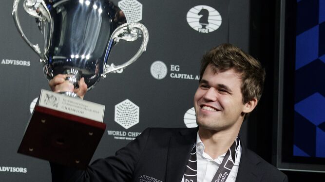 Carlsen celebra el triunfo mostrando el trofeo de campeón.