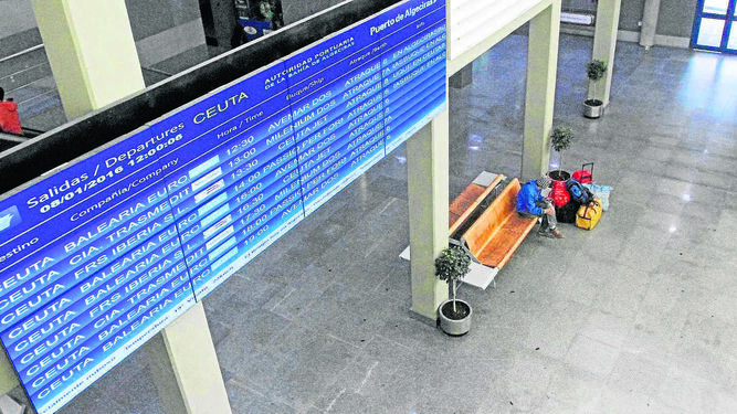 Un pasajero espera su turno para embarcar en un banco del vestíbulo de la estación marítima de Algeciras