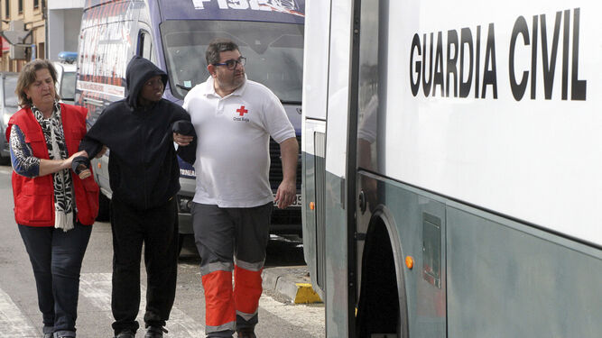 Dos voluntarios de Cruz Roja ayudan a una persona a subir al autobús de la Guardia Civil, ayer en Tarifa.