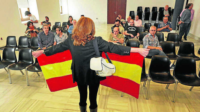 Una mujer despliega  una bandera de España en la Casa de Iberoamérica.