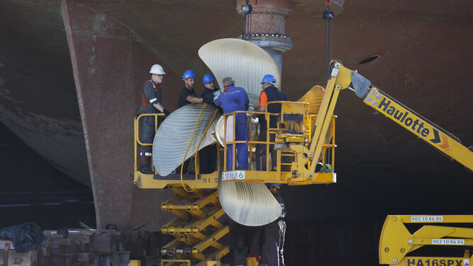 Trabajadores del astillero reparan la hélice de un barco.