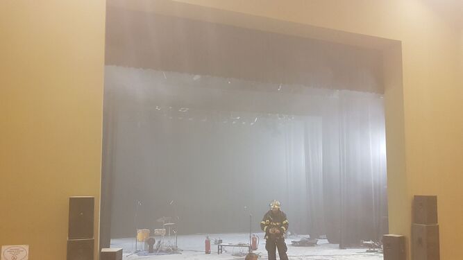 Varios bomberos y operarios en el escenario del teatro Alameda, la madrugada de ayer.