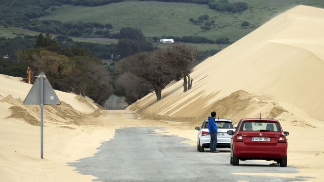 Dos coches parados en la A-2325, invadida por la arena de la duna.