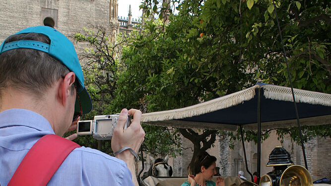 Un turista hace fotografías en la Plaza de la Virgen de los Reyes.