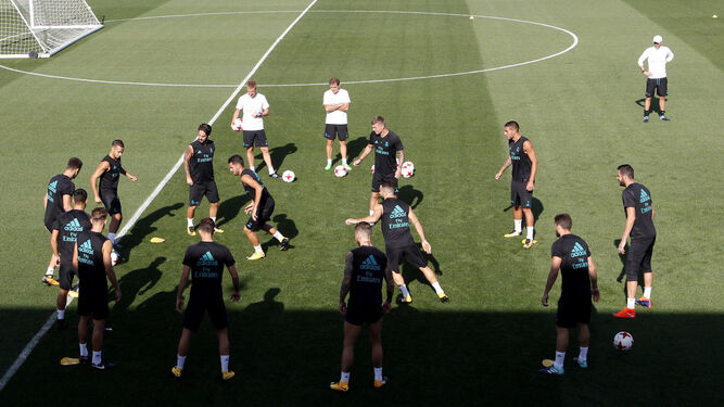 Varios jugadores del Real Madrid realizan un rondo en el entrenamiento de ayer en Valdebebas, con Zidane atento al fondo, a la derecha.