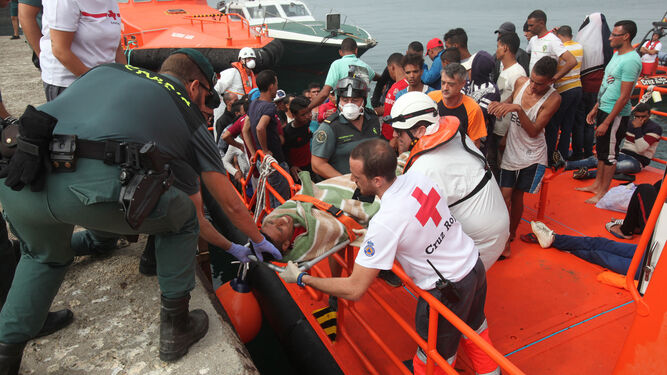 Miembros de la Guardia Civil, la Cruz Roja y Salvamento Marítimo participan en el traslado a tierra de uno de los migrantes rescatados.