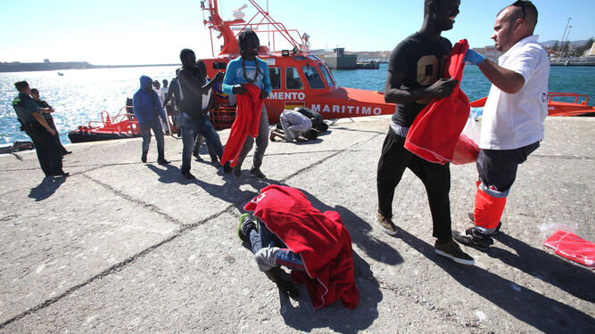Una de las personas rescatadas besa el suelo tras llegar al puerto de Tarifa.