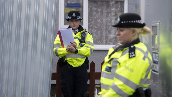 Dos oficiales de la policía británica,  junto a una zona acordonada en una dirección en Londres.
