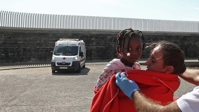 Una menor migrante es arropada con una manta de la Cruz Roja tras llegar al puerto de Tarifa, el pasado verano.