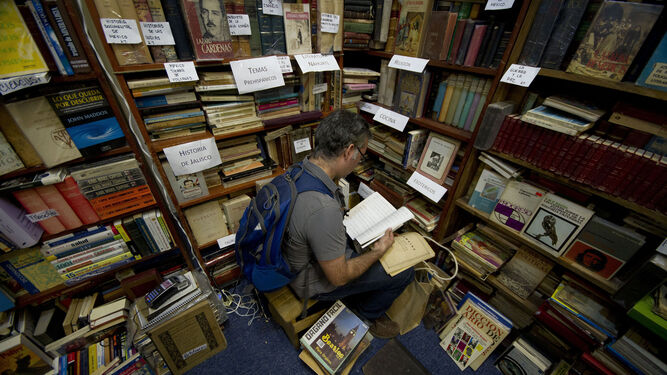 Un visitante de la FIL hojea libros en una de las casetas.