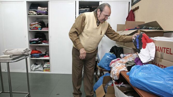 Un voluntario clasifica ropa para las personas del albergue.