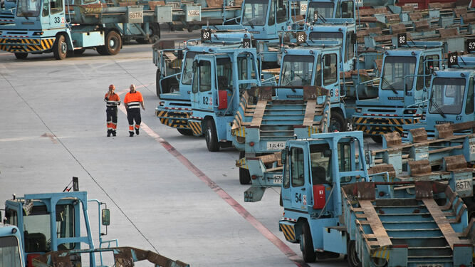 Dos estibadores del Puerto de Algeciras caminan junto a varias cabezas tractoras.