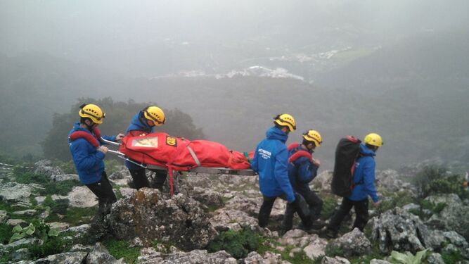 Los efectivos del Grupo de Rescate de Montaña, con sede en Ubrique, del Consorcio de Bomberos trasladando a una persona herida por la montaña.