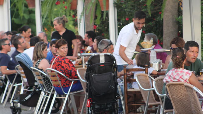 Un camarero atiende a un grupo de turistas en una terraza de un establecimiento en Conil, el verano pasado.