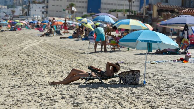 Una mujer bajo la sombrilla en la playa de El Rinconcillo de Algeciras