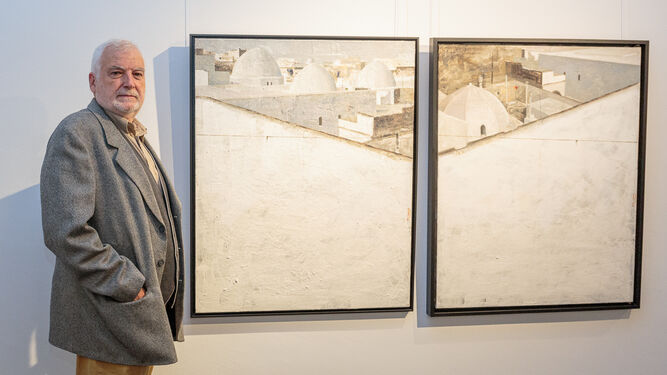 Manolo Cano posa ante dos de los cuadros que expone en Sevilla.