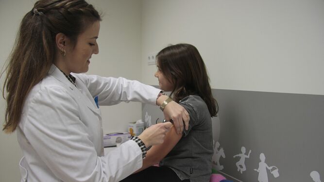 Una enfermera vacuna a una niña en una consulta.