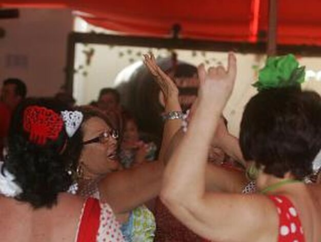 Mujeres vestidas de gitana bailan animadamente en el interior de una caseta.

Foto: Jose Maria Qui?s
