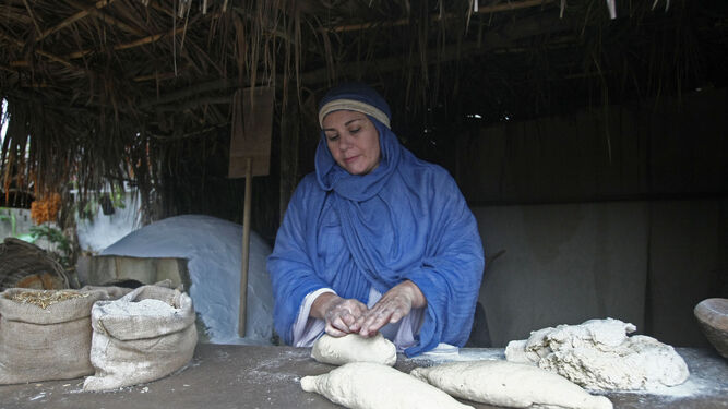 Una de las mujeres de Pelayo, vestida de época y amasando pan.