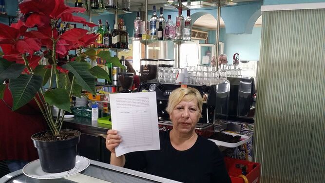 En el Bar Romino de El Saladillo, la trabajadora muestra la hoja para recoger firmas de los ciudadanos.