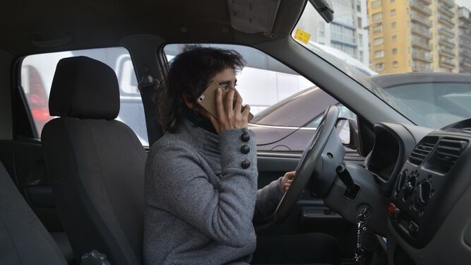 Imagen simulada de una mujer usando el móvil en el interior de su vehículo, en marcha.