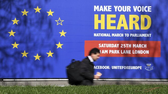 Un hombre pasa delante de un cartel con la bandera de la UE con una estrella sin colorear.
