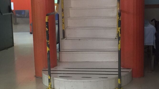 Una escalera con bandas de seguridad desgastadas en los peldaños.