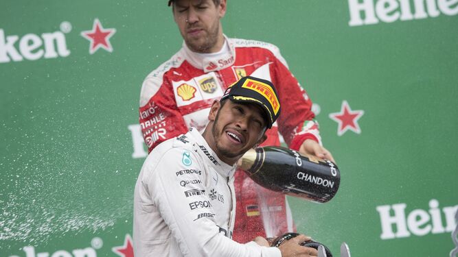 Sebastian Vettel y Lewis Hamilton se refrescan con champán en un podio.