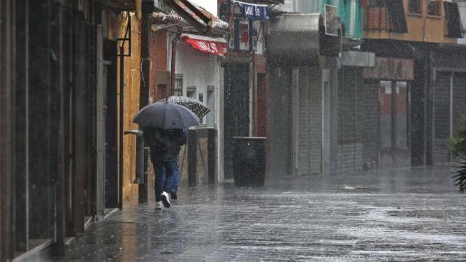Dos personas se resguardan de la lluvia y el viento en la calle Tarifa.