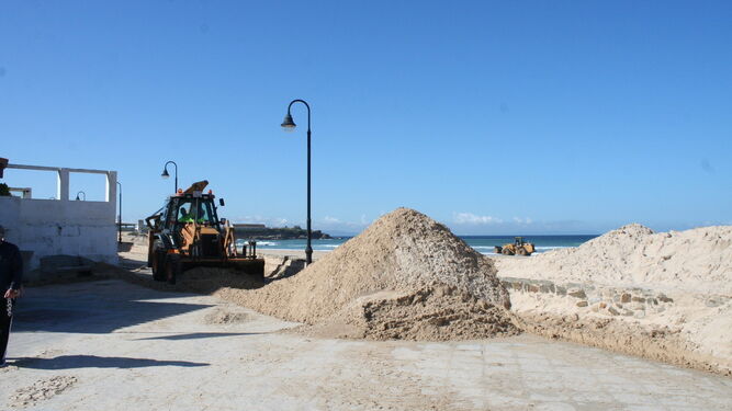 Una excavadora retira la arena acumulada en el paseo marítimo de Tarifa.