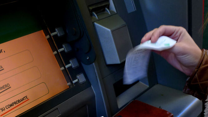 Un cliente sacando dinero de un cajero automático, en una imagen de archivo.