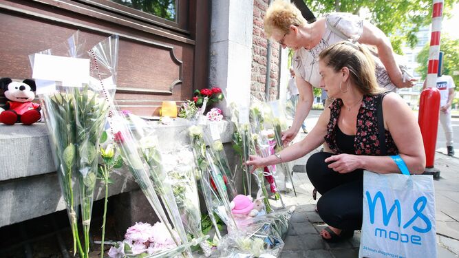 Dos mujeres colocan flores en homenaje a las víctimas de Lieja.