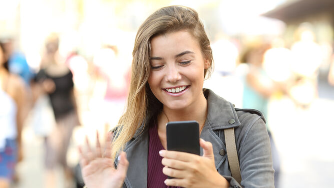 Una chica saluda a través de videollamada en su móvil.