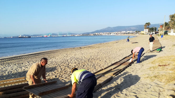 Varios operarios colocanm la pasarela de la playa.