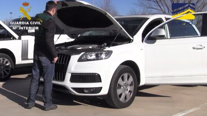 Dos agentes de la Guardia Civil inspeccionan uno de los coches recuperados.