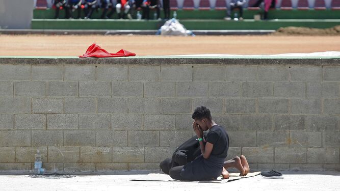 Dos personas rezan junto a un muro en el polideportivo de Los Cortijillos.