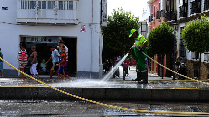 Un operario de la limpieza baldea una calle en San Fernando.