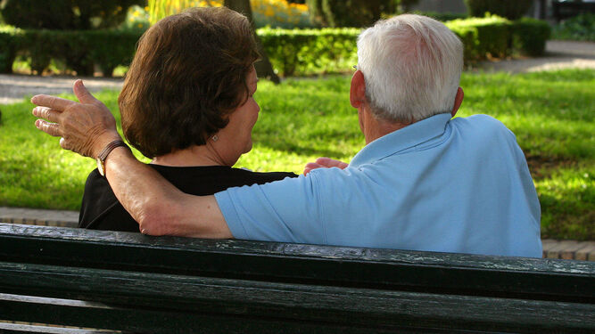 Una pareja de ancianos sentada en un banco del parque.