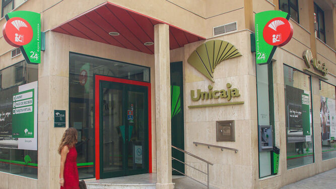 Una mujer pasa junto a una oficina de Unicaja Banco en Málaga capital.