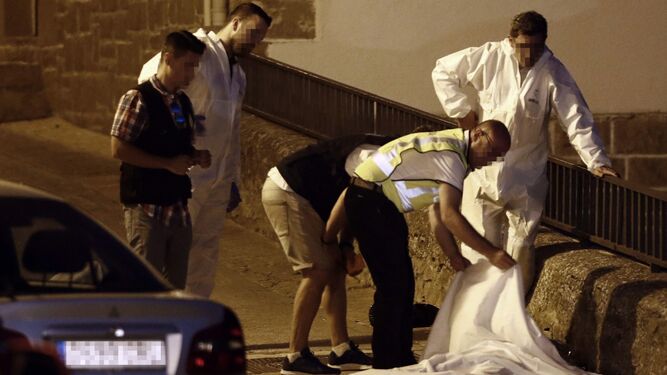 Agentes de la Guardia Civil tapan uno de los cadáveres.