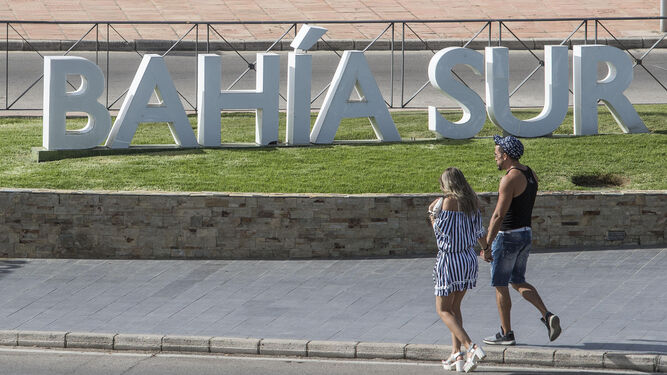 Una pareja camina junto al letrero colocado en el acceso de Bahía Sur.