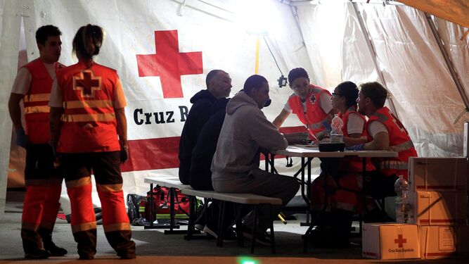 Miembros de Cruz Roja atienden a varios migrantes llegados este domingo al puerto de Algeciras.