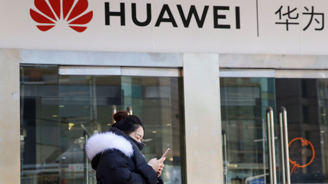 Una mujer pasa frente a una tienda de Huawei en Pekín.