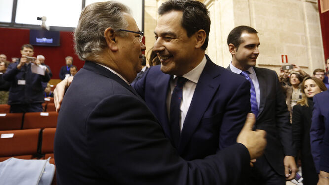 Juan Ignacio Zoido y Juanma Moreno se saludan en el salón de Plenos del Parlamento.