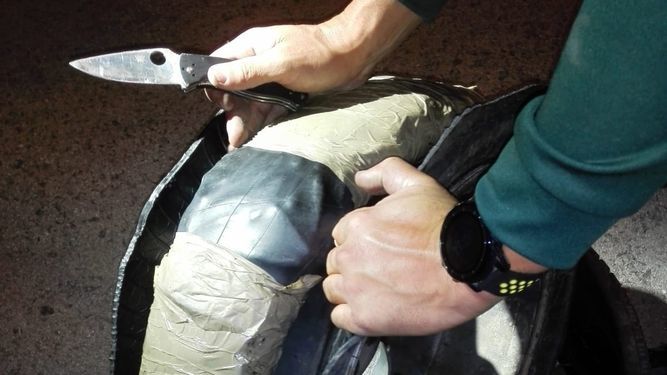 Un guardia civil muestra la droga encontrada en una rueda