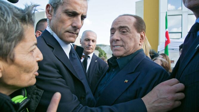 Berlusconi es custodiado por un escolta durante su visita a la localidad de Monserrato.