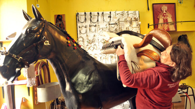 Ana María Garrido prueba una montura en un maniquí de caballo, en la tienda que la familia de guarnicioneros tiene en Villamartín.