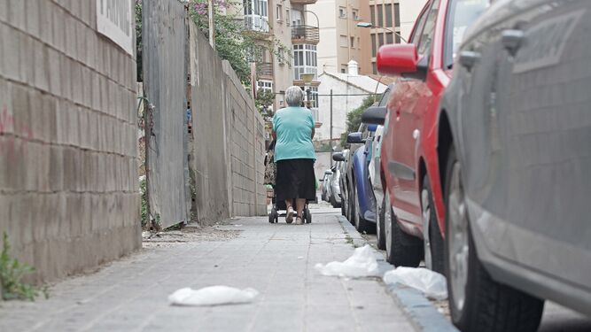 Una mujer camina en una calle junto a una hilera de aparcamientos.