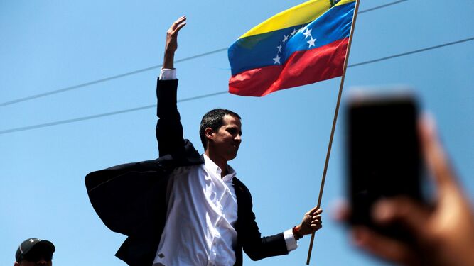 Guaidó saluda con una bandera venezolana a sus simpatizantes en el aeropuerto.